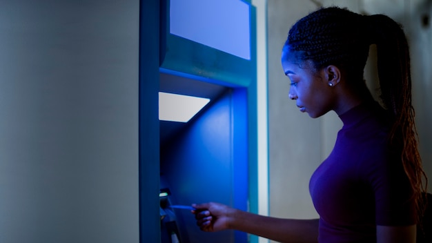 Femme noire utilisant le guichet automatique