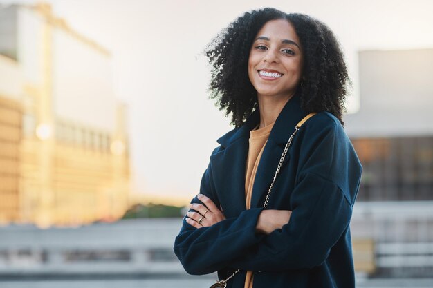 Femme noire ville et sourire portrait d'une personne par et bâtiment urbain se sentant détendu et heureux Liberté de voyage et bonheur d'une jeune femme en plein air avec un sac prêt pour voyager ou travailler