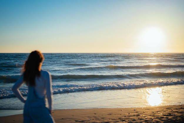 Une femme non focalisée regarde le coucher de soleil sur la mer