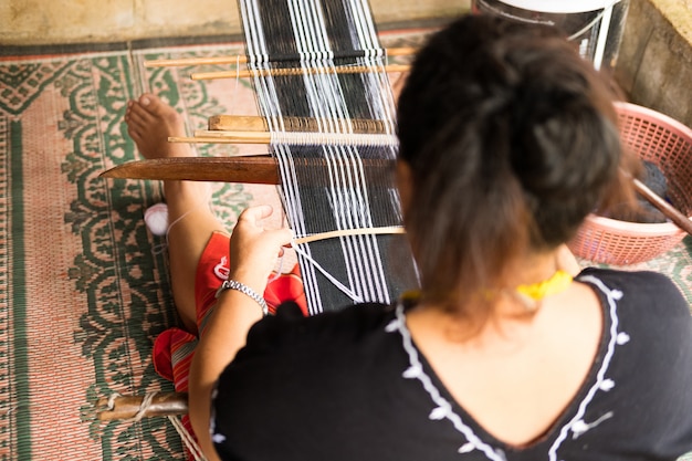 Une femme non identifiée appartenant à une minorité de tribus des collines tisse des tissus traditionnels