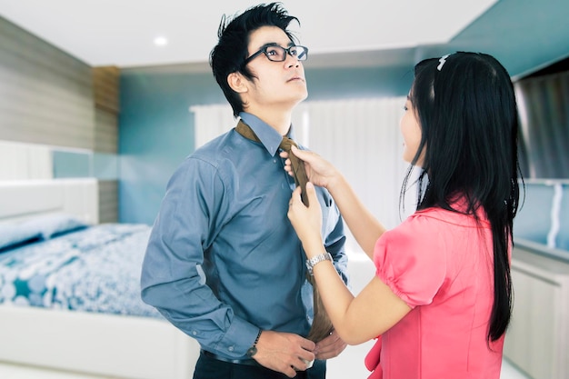 Femme nouant la cravate de son mari dans la chambre