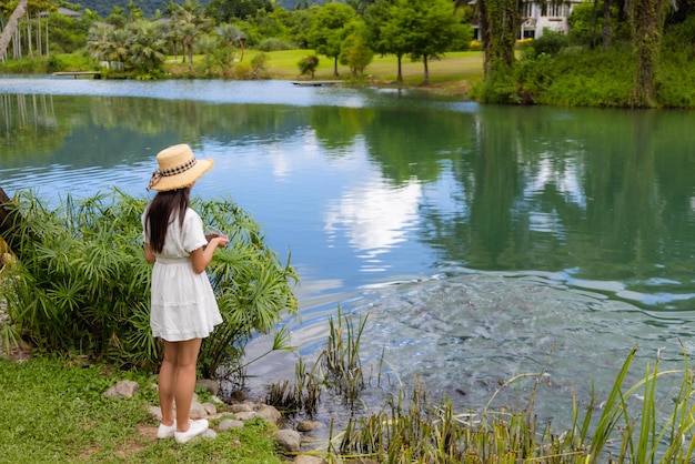 Une femme nourrit les poissons dans l'étang du jardin.