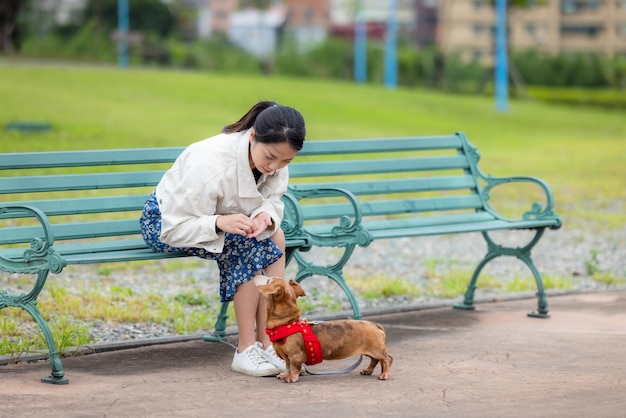 Une femme nourrit son chien dachshund dans le parc