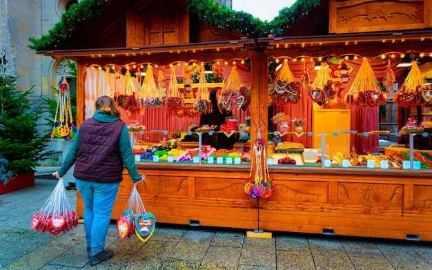 Femme avec de la nourriture de biscuits de pain d'épice sur le marché de Noël en Europe en hiver. Rue de nuit allemande Xmas et foire de vacances dans une ville ou une ville européenne, décembre. Église du Souvenir Kaiser Wilhelm à Berlin, Allemagne