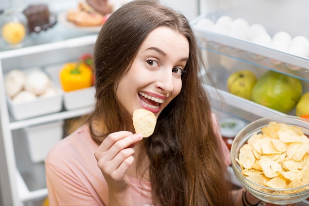 Femme avec de la nourriture près du réfrigérateur