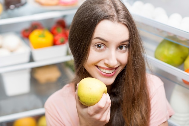 Femme avec de la nourriture près du réfrigérateur