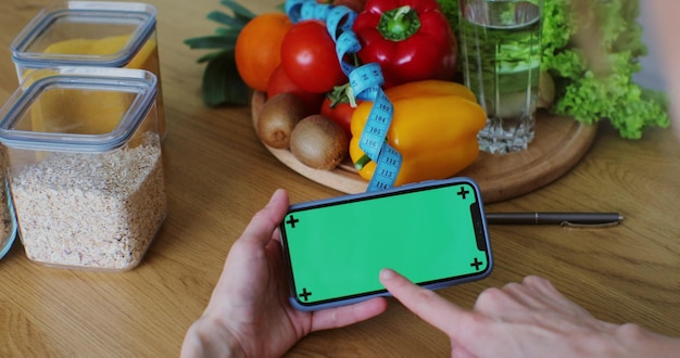 Photo femme nutritionniste avec des fruits et légumes sains à l'aide d'un smartphone avec écran vert écran vert personnalisable facile bon concept de nutrition et de régime alimentaire