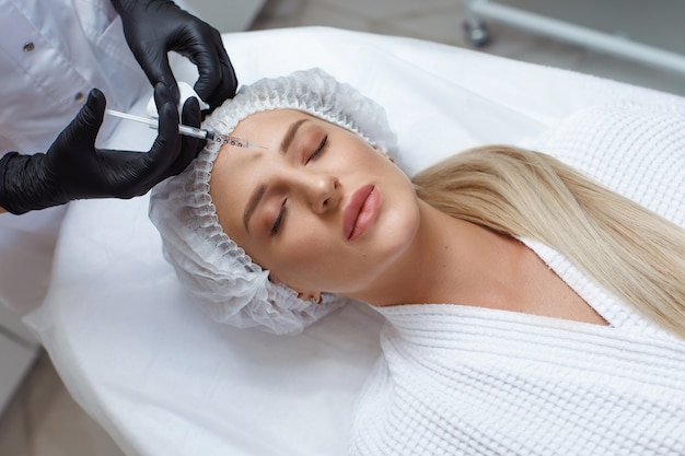 Femme obtenant une injection cosmétique de botox dans la joue, gros plan. Femme dans un salon de beauté. clinique de chirurgie plastique.