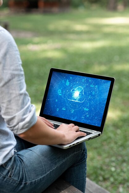 Femme occupée à taper sur son ordinateur portable assise à l'extérieur de son jardin Vue latérale Actif accomplissant du travail à domicile Fille restant seule à l'air libre Terminant des projets de travail à distance