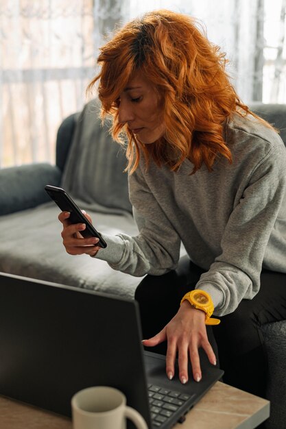 Photo femme occupée utilisant un smartphone et un ordinateur portable à la maison