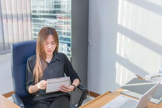 Femme officier asiatique regardant le calendrier dans la réunion de bureau le mois prochain