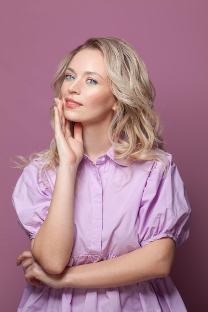 Femme optimiste mignonne aux cheveux blonds portant un chemisier rose sur un fond rose vif portrait de studio