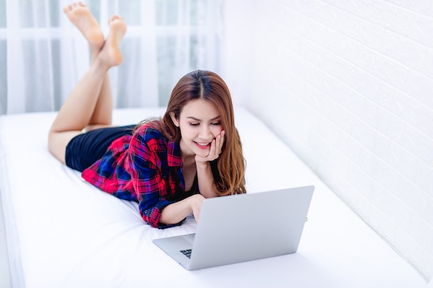 La femme et l'ordinateur dans la salle blanche Travail heureux Le concept de travail heureux à la maison