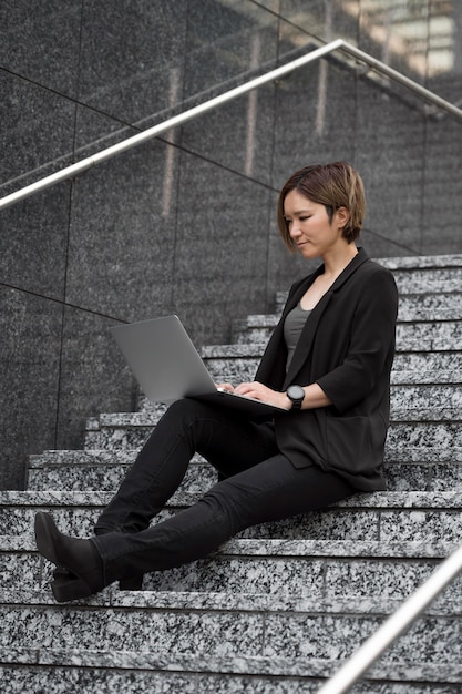 Femme avec ordinateur portable dans les escaliers plein coup