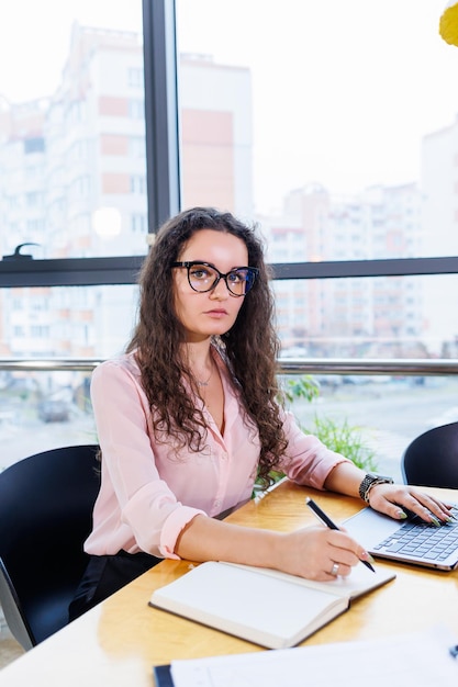 Femme à l'ordinateur portable, organisant des équipes commerciales et des plans d'investissement tout en travaillant sur un nouveau projet de démarrage avec des tableaux, des graphiques et des accessoires commerciaux sur le lieu de travail.