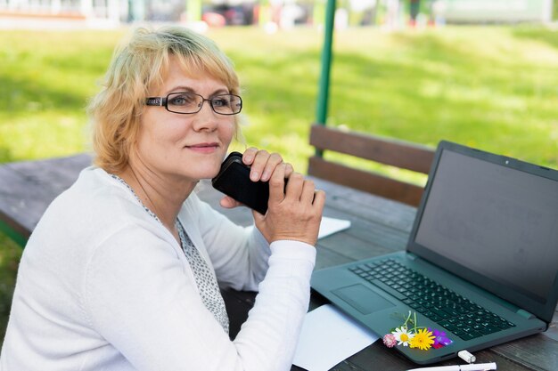Une femme avec un ordinateur portable regarde un document dans un café, un bureau