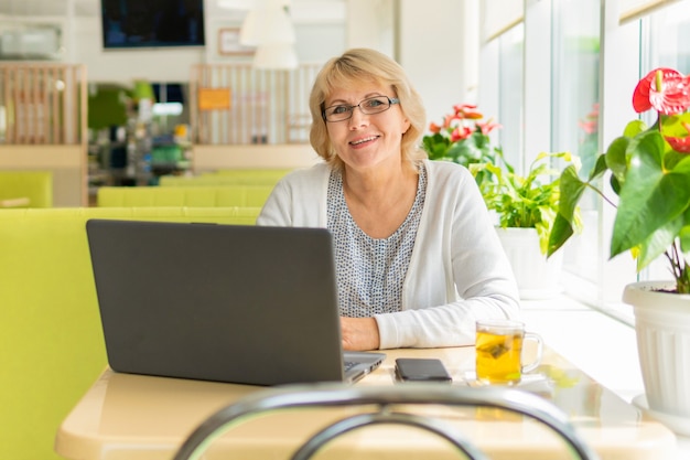 Une femme avec un ordinateur portable travaille dans un café au bureau