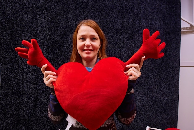 Une femme avec un oreiller en forme de coeur rouge pour la saint valentin