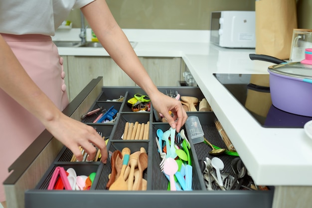 Femme organisant des ustensiles de cuisine.