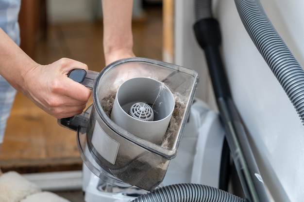 Femme ouvrant le filtre à poussière hors des tâches ménagères de l'aspirateur