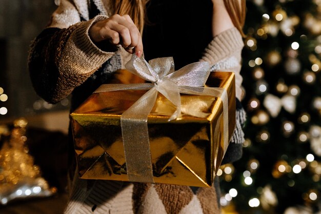 Une femme ouvre un cadeau de Noël en gros plan sur les mains