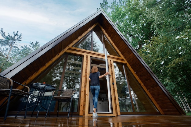 La femme ouvre la porte d'un chalet de forêt et entre à l'intérieur de la vue arrière