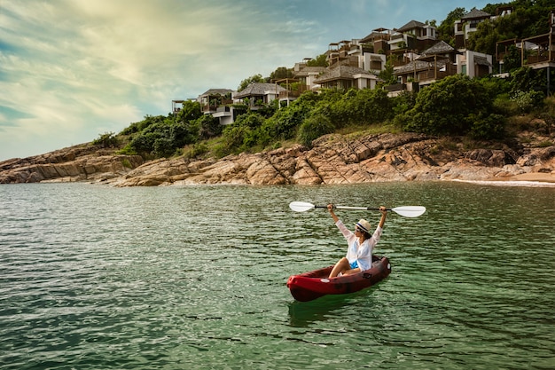 Femme pagayant un kayak pour explorer la baie tropicale calme avec des montagnes calcaires aux Maldives, l'île du village de Samui, Thaïlande.