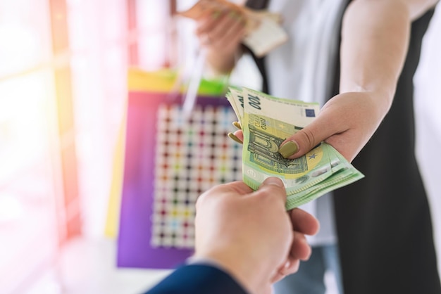 Une femme paie de l'argent en euros en achetant des vêtements dans le magasin