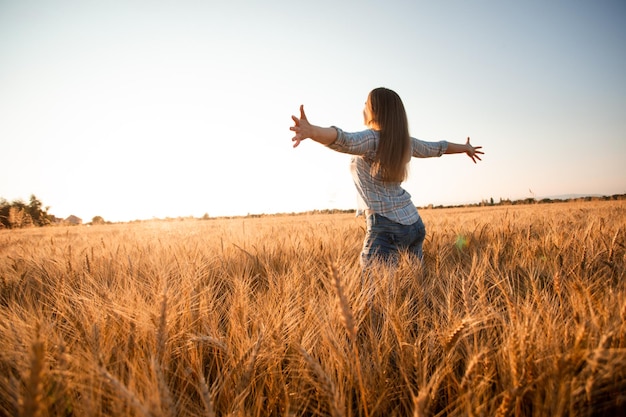 Femme paisible accueillant le soleil levant dans le champ