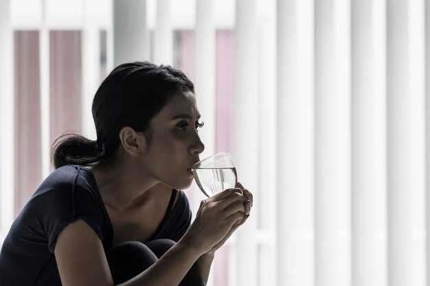 Une femme pâle buvant un verre d'eau.