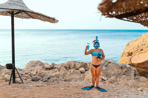 Une femme en palmes et un masque pour faire du snorkeling au bord de la mer pendant les vacances de Noël