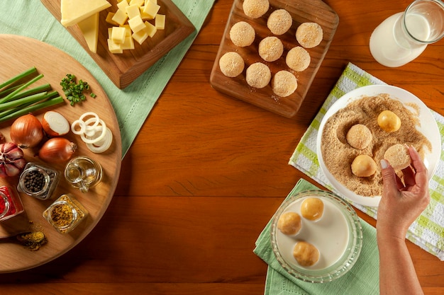 Femme panant du fromage brésilien croquette farcie bolinha de queijo sur une table en bois Vue de dessus