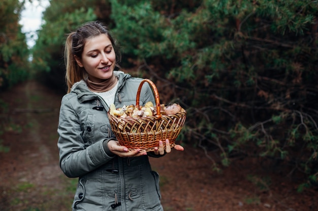 Femme avec panier de champignons gras dans la forêt d'automne. Ramasser des champignons biologiques frais et glissants