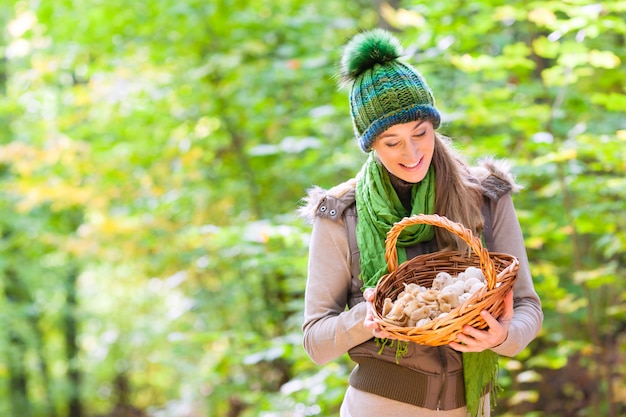 Femme avec panier rempli de champignons en forêt