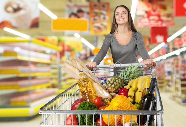 Femme avec panier shopping en supermarché