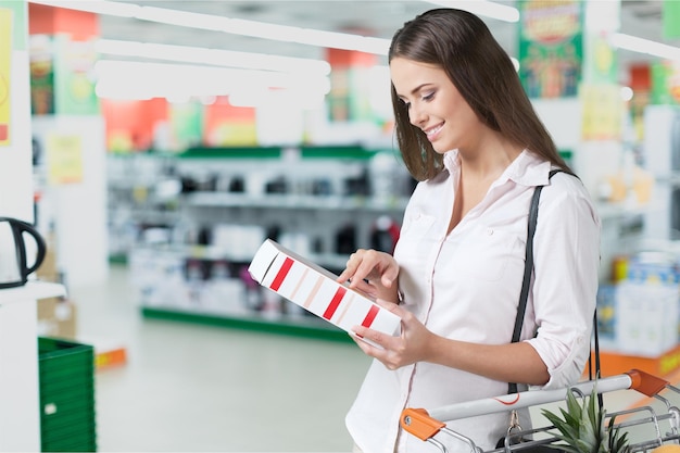 Femme avec panier shopping en supermarché