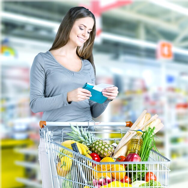 Femme avec panier shopping en supermarché