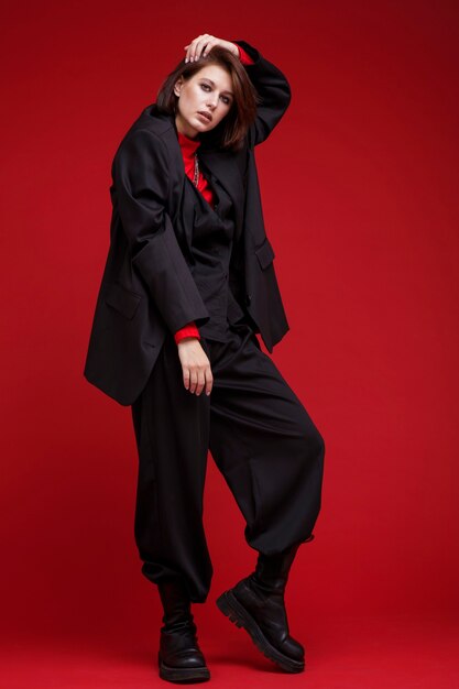 Femme en pantalon de costume noir surdimensionné haut sur fond rouge Coupe de cheveux Bob Studio Shot Rebel classic