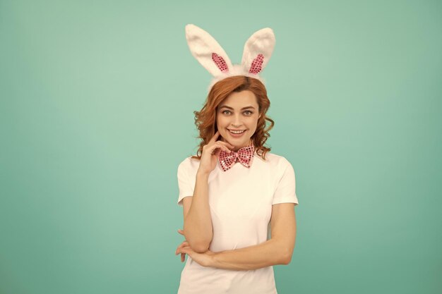 Femme de Pâques souriante avec des oreilles de lapin sur fond bleu