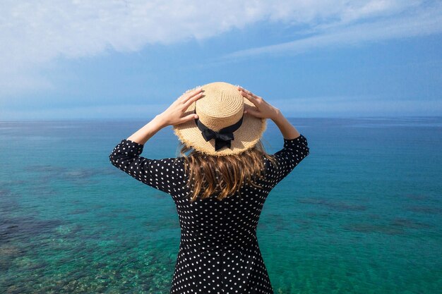 Femme par derrière en chapeau de paille contre le ciel