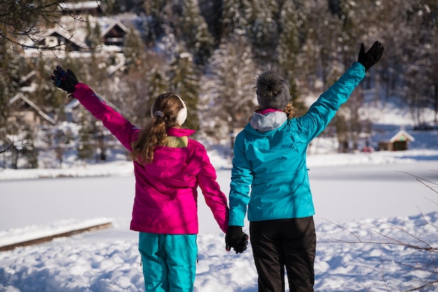 Photo femme par fille avec les bras levés dans la neige pendant l'hiver