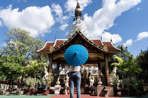 femme avec un parapluie bleu devant un temple bouddhiste