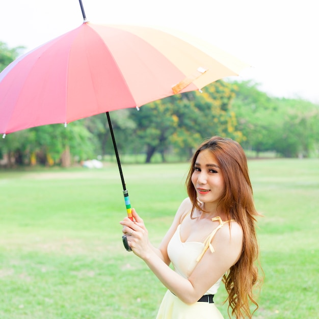 Femme avec un parapluie debout sur la pelouse.