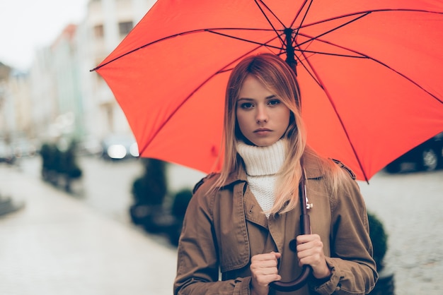 Femme avec parapluie. Jolie jeune femme portant un parapluie et regardant la caméra en se tenant debout dans la rue