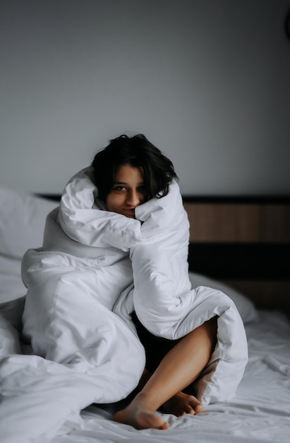 Photo femme paresseuse enveloppée dans une couverture douce assise dans un lit douillet