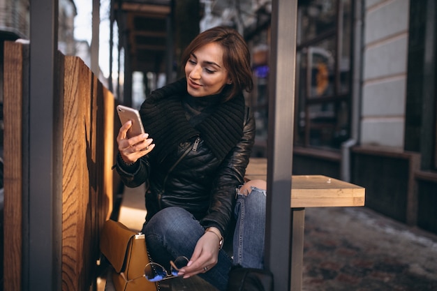 Femme parlant au téléphone et assis sur un banc dans la rue