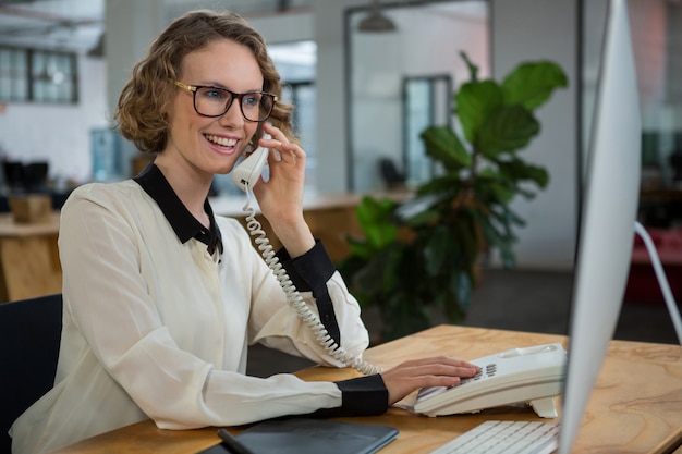 Femme parlant au téléphone fixe au bureau