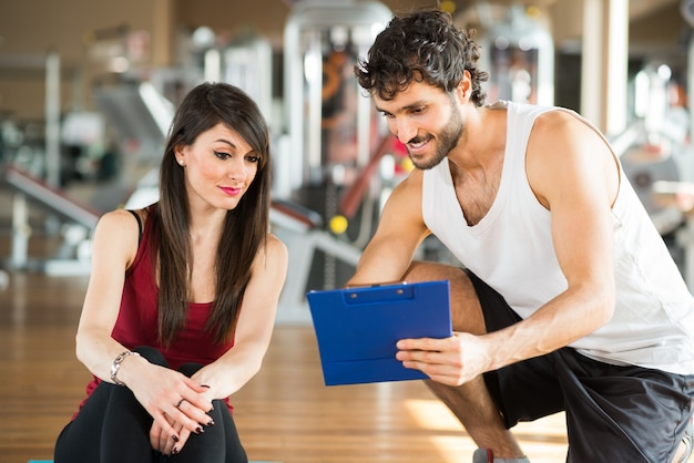 Photo femme parlant à son entraîneur personnel dans une salle de sport