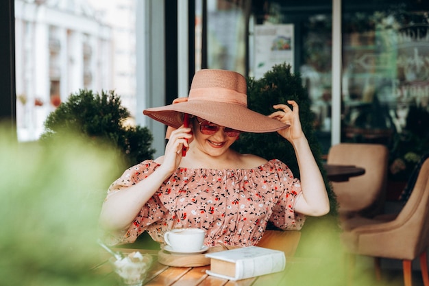 Une femme parle au téléphone Une femme avec un téléphone portable est assise dans un café une femme en robe et un chapeau dans un café