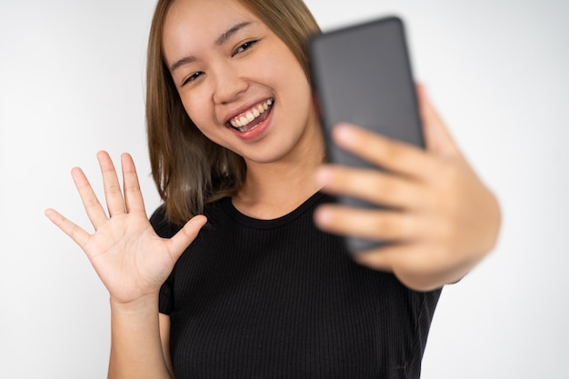 Une femme passe un appel vidéo à l'aide d'un téléphone portable en disant bonjour le geste